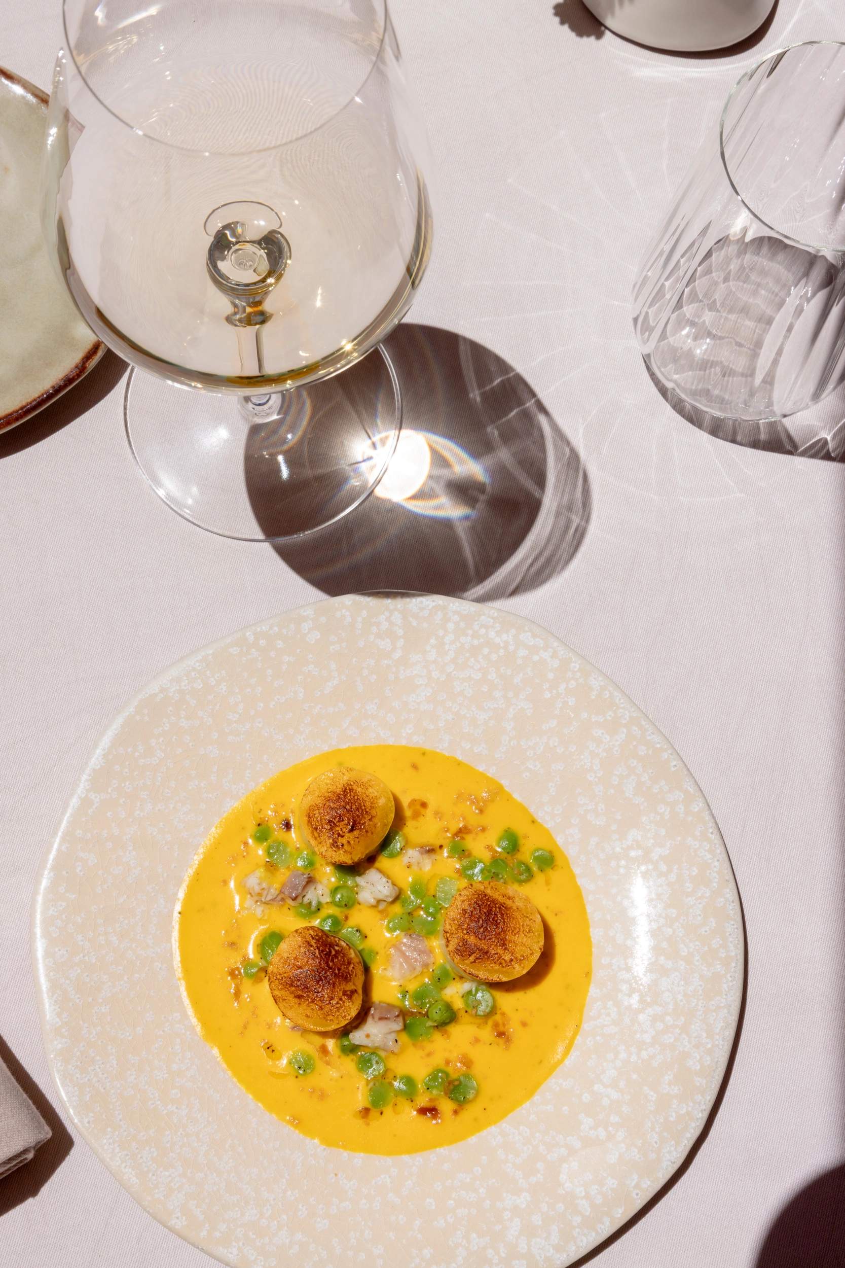 Restaurant gastronomique avec assiette de scallops à sauce safran et verre de vin blanc