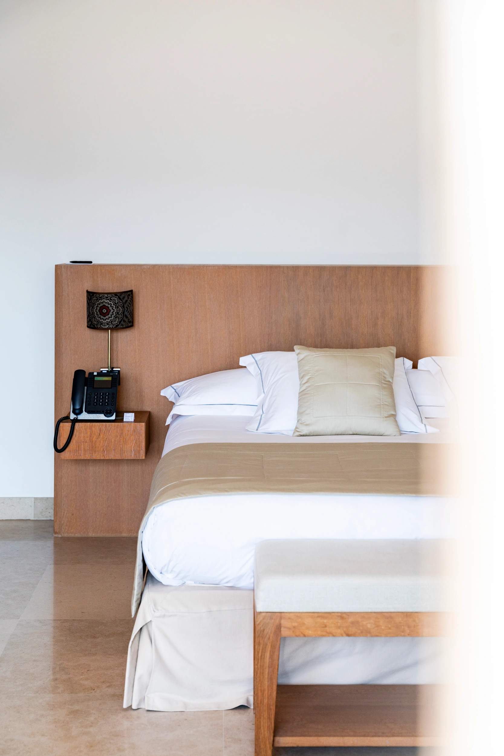 Chambre d'hôtel de luxe avec lit double, headboard en bois clair et téléphone